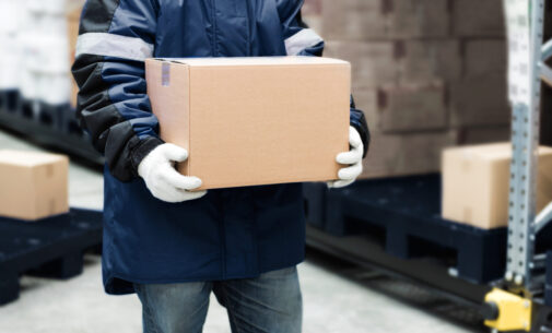 Worker carrying a goods box in a large frozen warehouse.Export-Import Logistics system concept