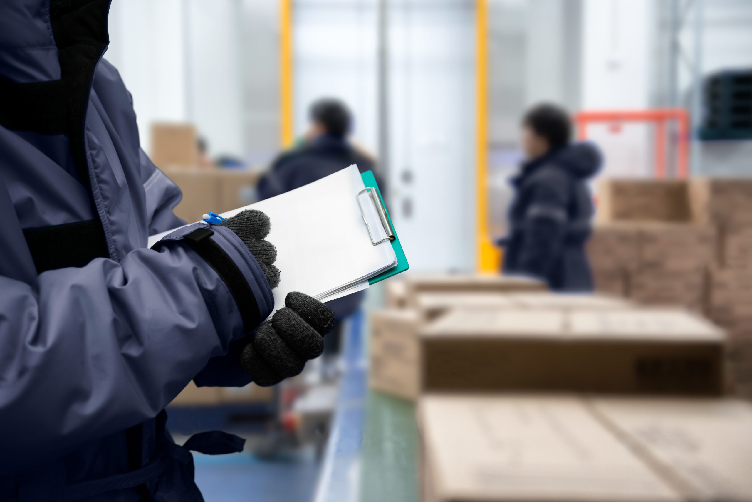 Closeup shooting hand of worker with clipboard checking goods in freezing room or warehouse